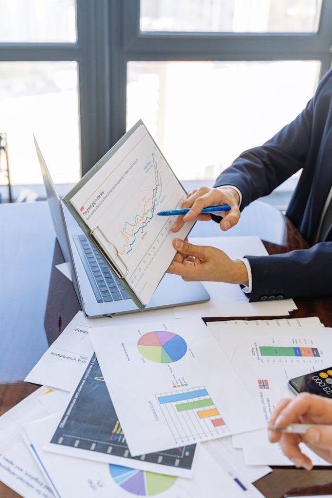 person-in-black-suit-jacket-holding-white-paper-5816299 Business professionals discussing financial graphs and charts in an office setting.