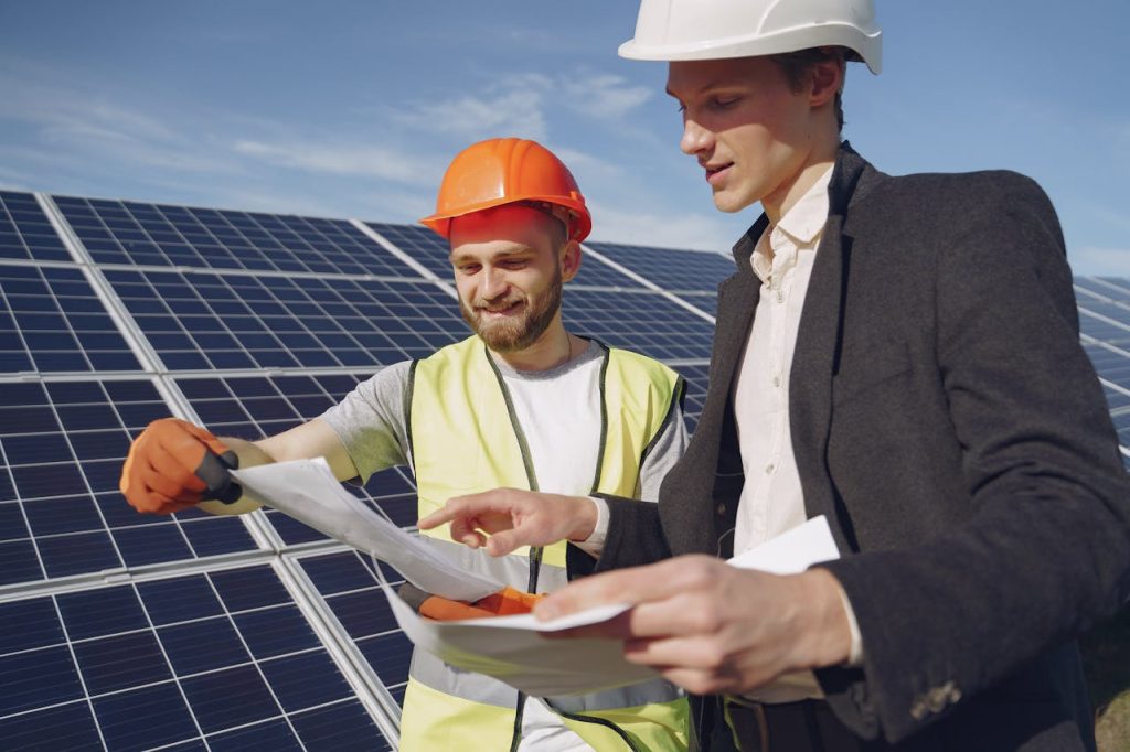 two-electricians-standing-near-the-solar-panels-4254157 Two engineers reviewing plans for solar panel installation, representing teamwork in renewable energy.